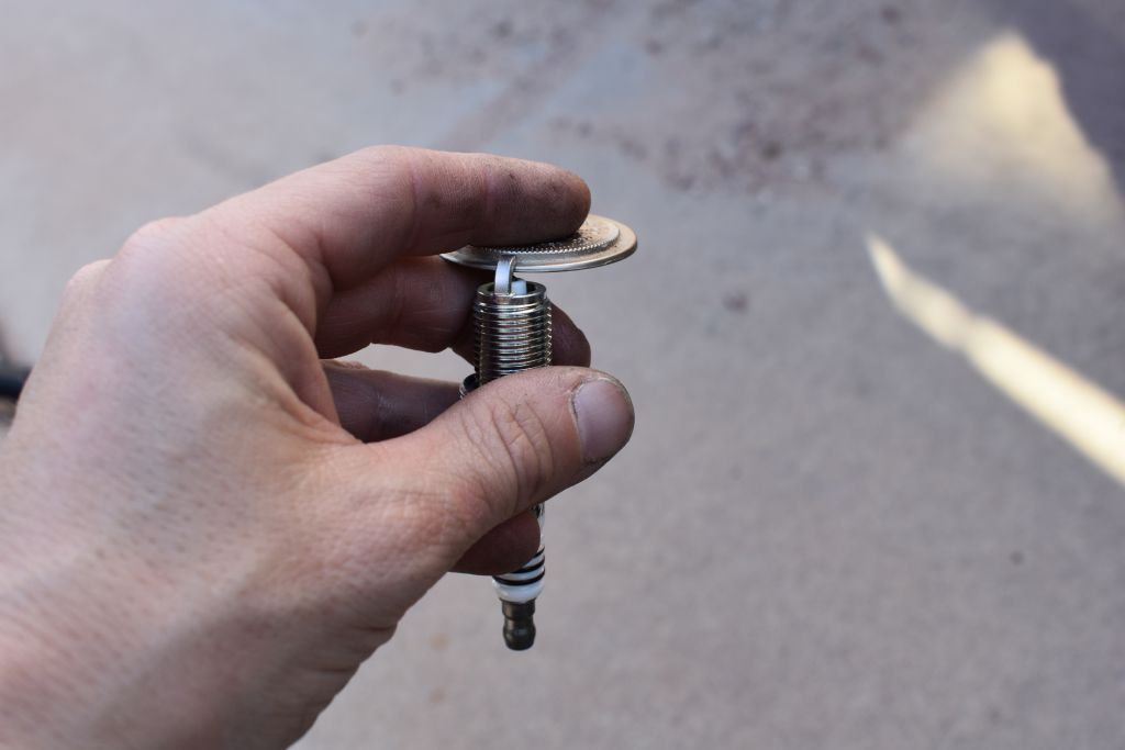 Man gaps a spark plug with a disc style spark plug gauge